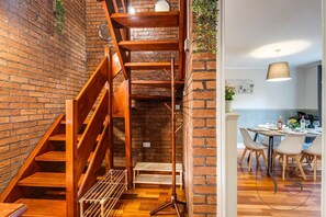 A wooden staircase with a metal railing, a dining area with a table and chairs, and a hanging light fixture. - 4BR Family Home with Jacuzzi Near Birmingham (West Midlands)