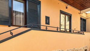 Un edificio con balcón, ventana con reja de metal y puerta con marco negro.