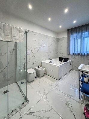 Un baño moderno con ducha envuelta en vidrio, una bañera, un inodoro y un tocador con lavabo.