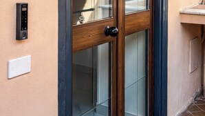 Una puerta con cerradura electrónica, felpudo y suelo de baldosas.