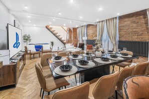 Uma sala de jantar moderna com uma mesa comprida posta para seis pessoas, rodeada por cadeiras confortáveis.