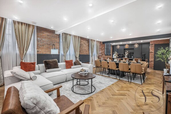 Uma sala moderna com sofá, mesa de centro e área de jantar com cadeiras.