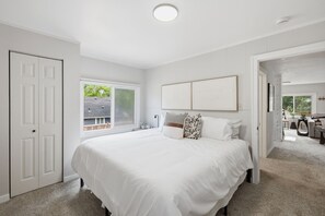 A bedroom with a large bed, a window, and a door leading to a living area. - Fabulous 2-bedroom apartment in welcoming Eugene for your stay (Eugene)