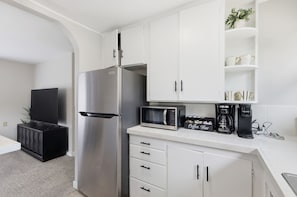 A modern kitchen with white cabinets, a stainless steel refrigerator, a microwave, a coffee maker, and a flat-screen TV. - Fabulous 2-bedroom apartment in welcoming Eugene for your stay (Eugene)