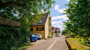 Eine Wohnstraße mit Häusern, parkenden Autos und blauem Himmel.