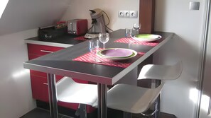 A compact kitchen with a dining table, chairs, and a coffee maker.