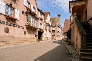 A narrow street lined with traditional European buildings, a clear sky, and a sign reading 'AU RAISIN D'OR'. - Gîte Lecaillon, Mountain View (Mittelbergheim)