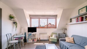Ein modernes Wohnzimmer mit einer Couch, Sesseln, einem Couchtisch, einem Fernseher und einem Bücherregal.