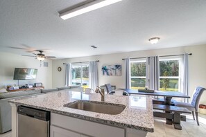 Eine moderne Küche mit Granit Arbeitsplatte, einem Geschirrspüler und einem Essbereich mit Tisch und Stühlen.