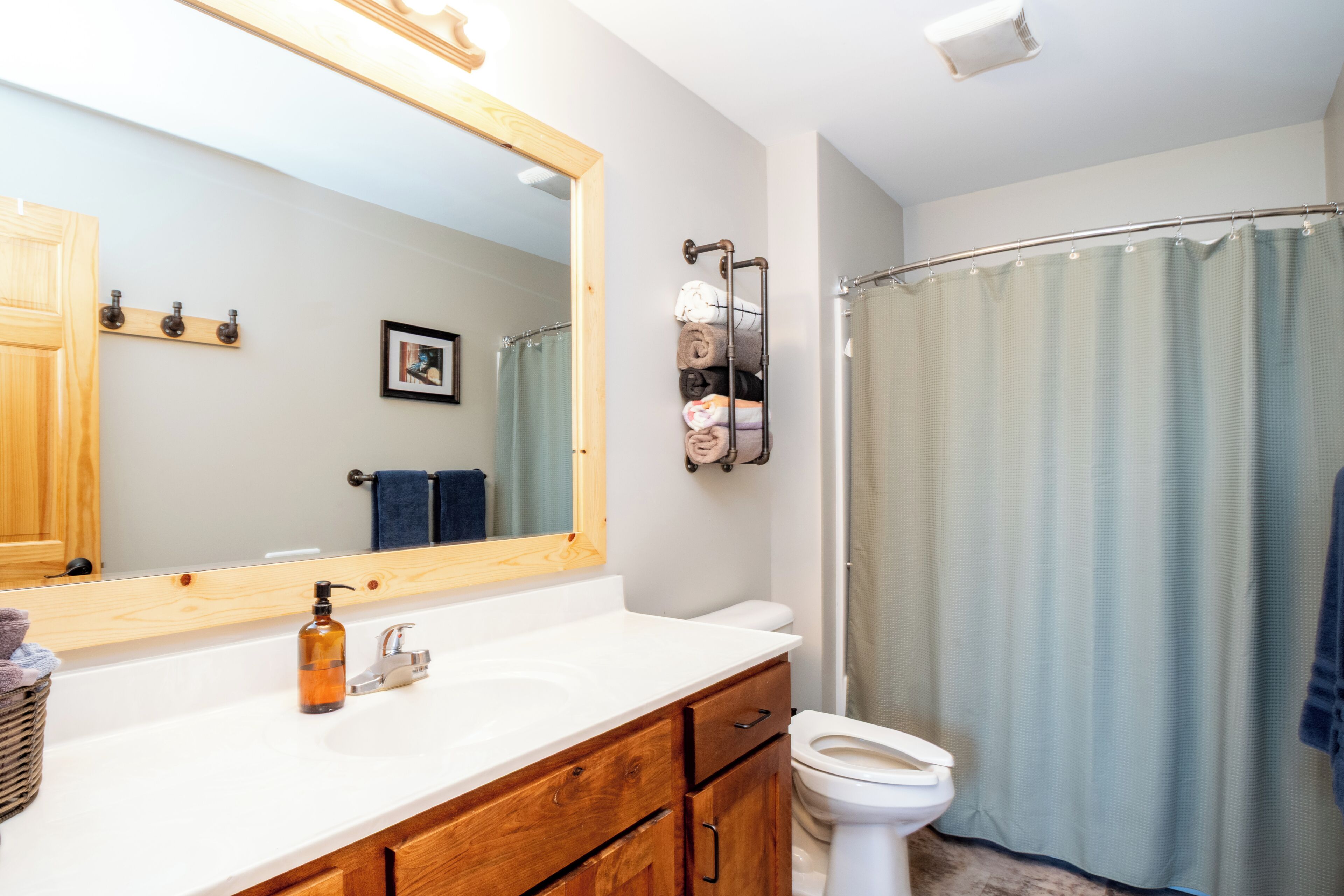 Un baño con tocador de madera, un espejo grande, un inodoro y una cortina de ducha.