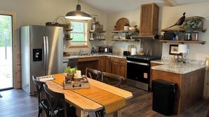 Una cocina moderna con una isla central, electrodomésticos de acero inoxidable, armarios de madera y un colgante de luz.