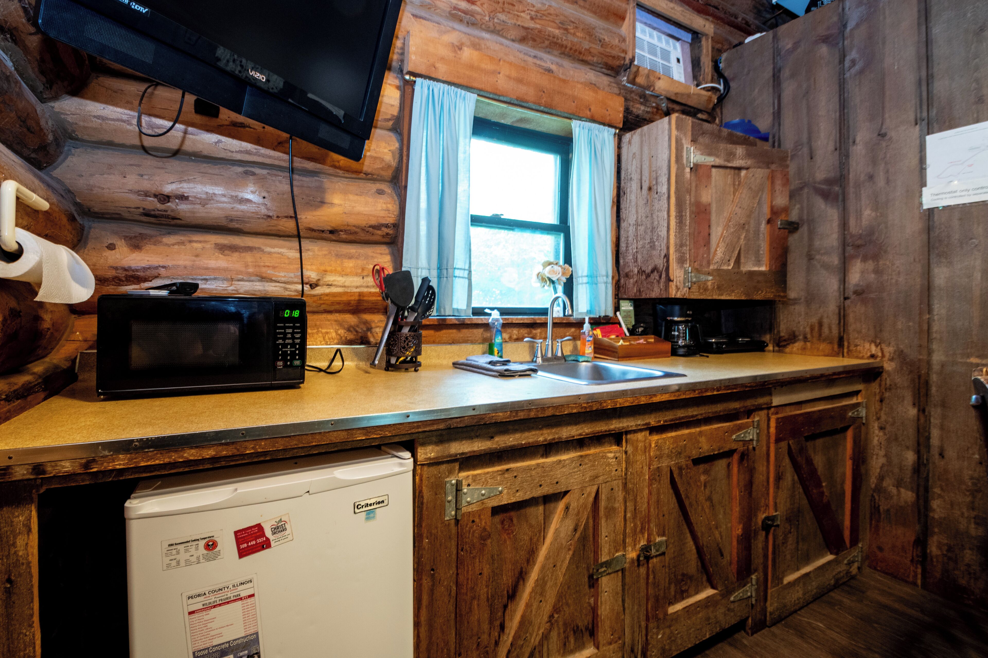 A kitchen with a microwave, sink, and wooden cabinets.