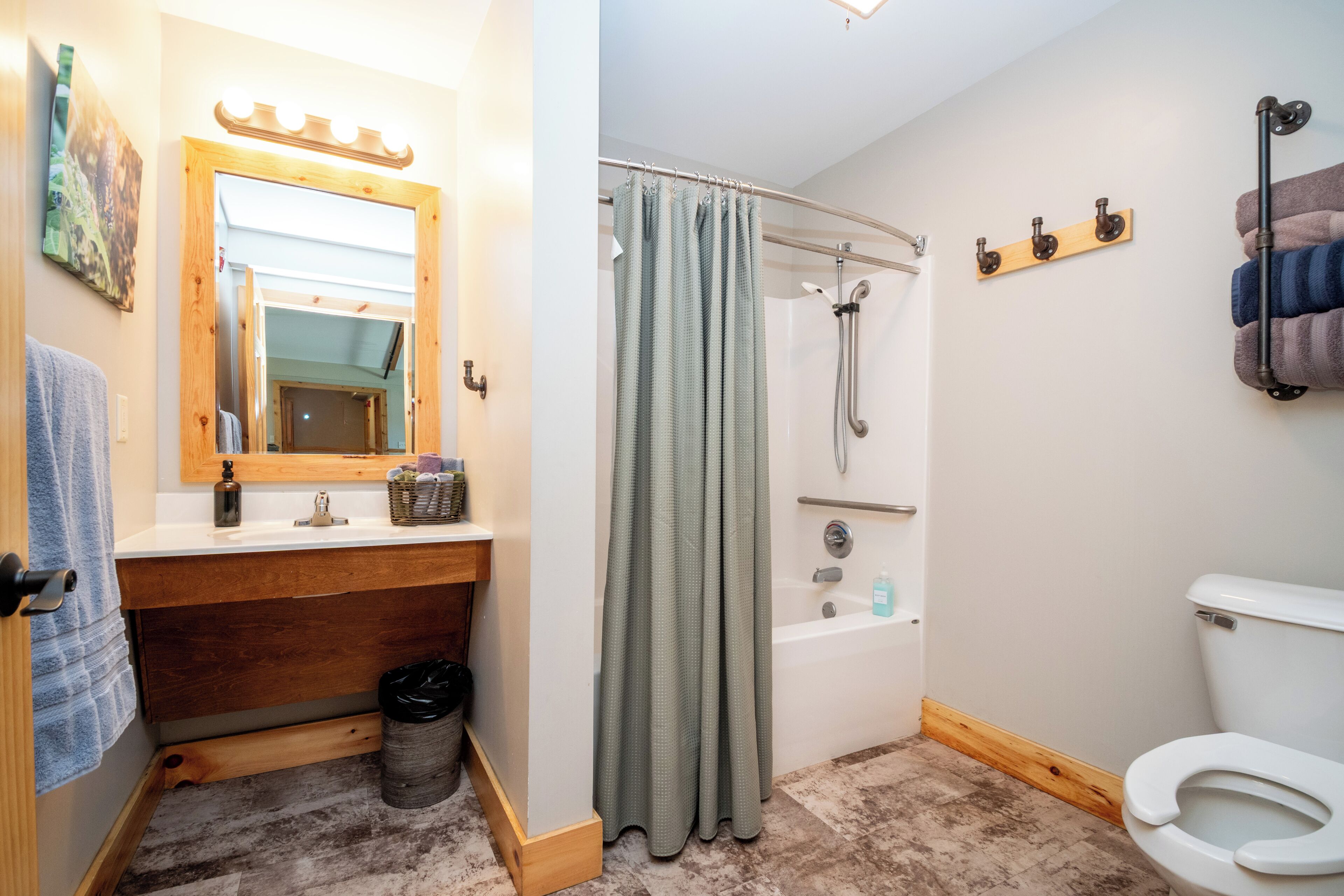 A bathroom with a wooden vanity, a shower with a glass door, a toilet, and a towel rack.