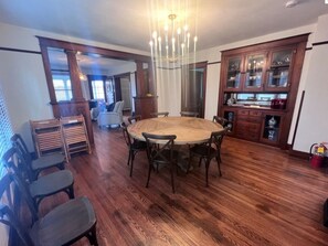 A dining area with a round wooden table and chairs, a chandelier, and a wooden cabinet with glass doors.