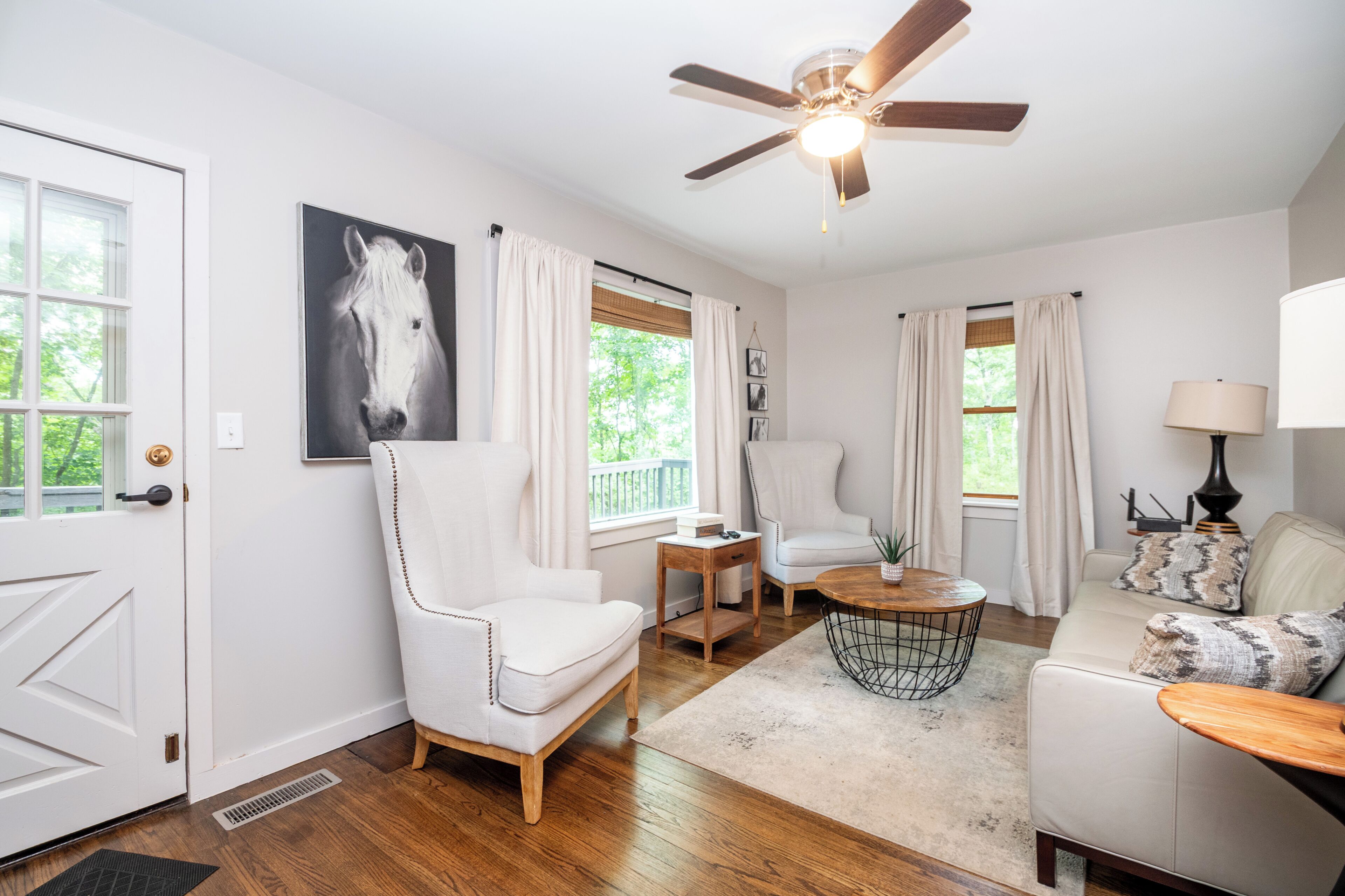 A living room with a ceiling fan, a white sofa, a coffee table, and a chair.