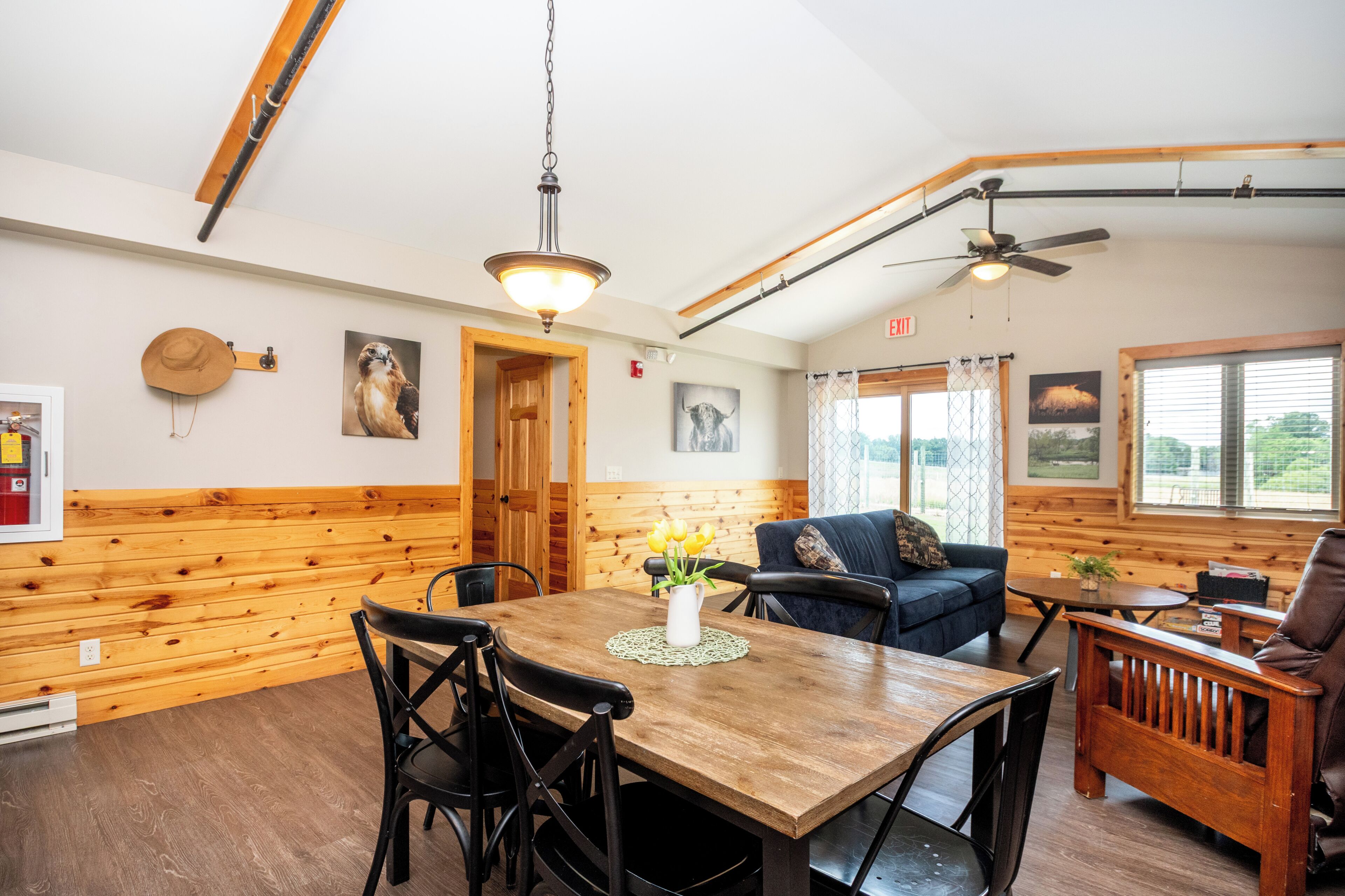 A dining area with a wooden table and chairs, a blue sofa, and a ceiling fan.