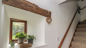 A staircase with a wooden handrail, a white wall, a window with plants, and a heart-shaped decoration. - Over Brow Cottage (Coniston)