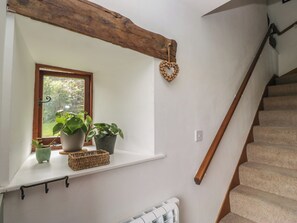 Eine Treppe mit hölzernem Geländer, einer weißen Wand, einem Fenster mit Pflanzen und einer herzförmigen Dekoration.