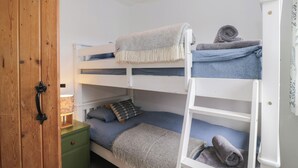 A bunk bed room with a wooden door, a green nightstand, and a white ladder. - Over Brow Cottage (Coniston)