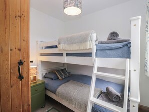 Ein Schlafraum mit Etagenbett, einer Holztür, einem grünen Nachttisch und einer weißen Treppe.