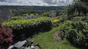 A garden with a view of a house, a pathway, and a chair. - Over Brow Cottage (Coniston)
