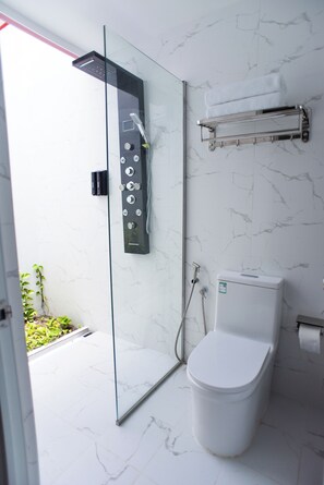 A modern bathroom with a glass-enclosed shower, a toilet, and a towel rack. - Paradise Palms (Thoddoo)