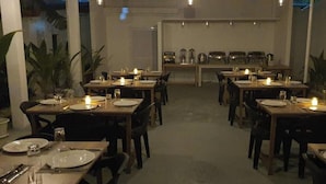 Un restaurante con varias mesas dispuestas para comer, cada una con platos, cubiertos y velas.