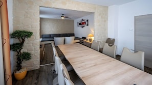 Ein modernes Zimmer mit einem Holztisch, einer Couch, einem Fernseher und einer Steinwand.