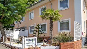 A building with multiple windows, a palm tree, and a sign indicating a city hotel. - City Holiday Home Daun in Daun – for 14 Guests (210 m²) (Daun)
