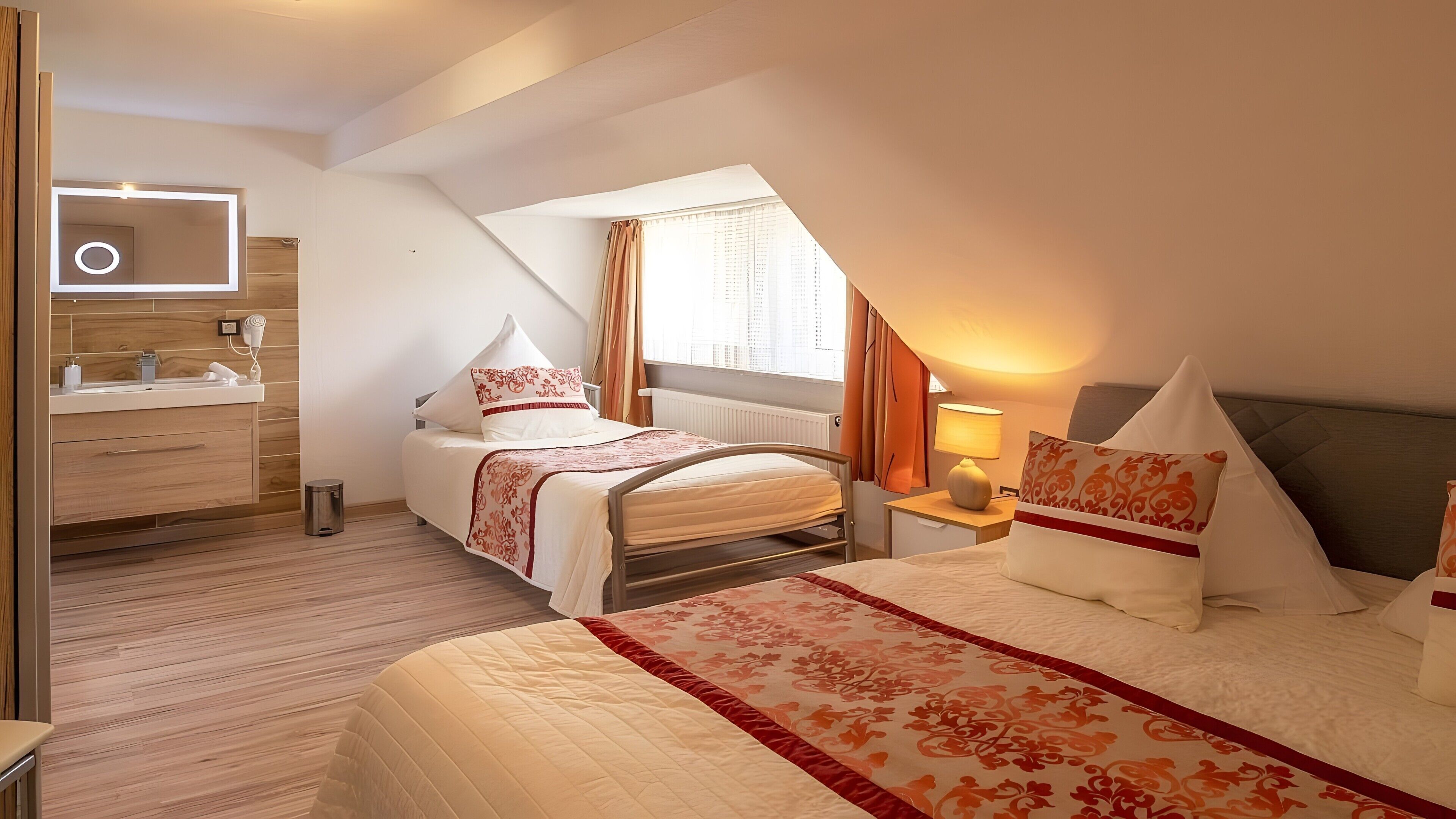 Una camera da letto con un letto, comodino, lampada e bagno con specchio e lavandino.