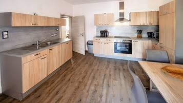 Una cocina moderna con armarios de madera, horno empotrado y pileta de acero inoxidable.