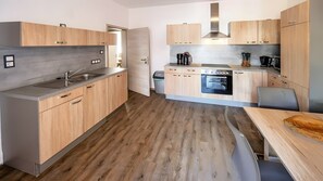 A modern kitchen with wooden cabinets, a built-in oven, and a stainless steel sink. - City Holiday Home Daun in Daun – for 14 Guests (210 m²) (Daun)