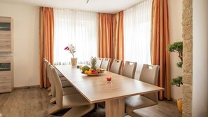 A modern dining area with a wooden table, beige chairs, and a fruit bowl. - City Holiday Home Daun in Daun – for 14 Guests (210 m²) (Daun)