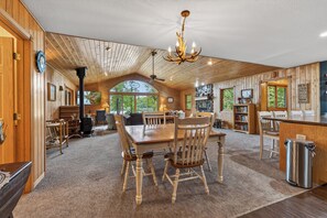 Una cocina amplia con armarios de madera, un comedor con una mesa grande y sillas, y vistas al exterior a través de un ventanal.