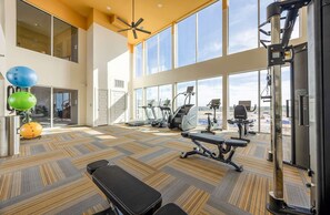 Un gimnasio espacioso con máquinas de cardio, banco de pesas y pelotas de ejercicio.