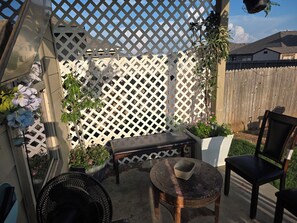En terrasse med en træbænk, et lille bord og en stol.