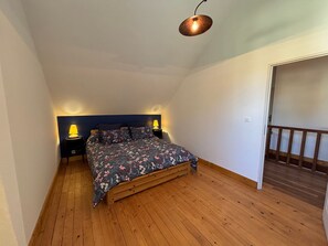 A bedroom with a wooden floor, a bed with floral bedding, two bedside lamps, and a ceiling light fixture. - At Patricia's: A spacious townhouse in the countryside in Graçay (Graçay)