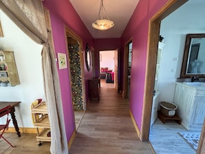 A hallway with wooden flooring, a hanging light fixture, a wooden cabinet, and a television on the right. - At Patricia's: A spacious townhouse in the countryside in Graçay (Graçay)