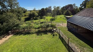 Paesaggio rurale con un fienile, prati erbosi e alberi.