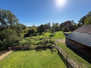 Ländliche Landschaft mit Scheune, Wiesen und Bäumen.