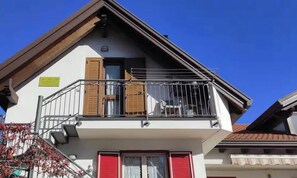 Een gebouw met twee verdiepingen, een balkon, een raam en een deur.