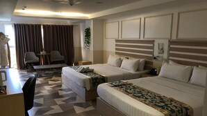 A hotel room with two beds, a desk, chairs, a bench, and a large window with curtains. - Sunday Sky Hotel in Korean Town Angeles, Near Clark International Airport (Angeles City)