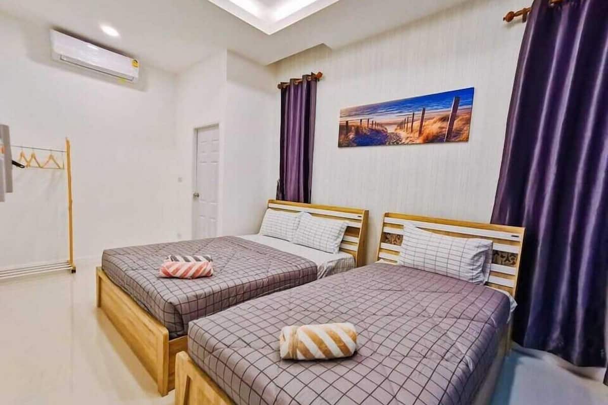 A hotel room with two beds, a painting on the wall, and an air conditioning unit.