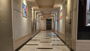 A hotel corridor with a tiled floor, doors, and framed artwork on the walls. - Sunday Sky Hotel in Korean Town Angeles, Near Clark International Airport (Angeles City)