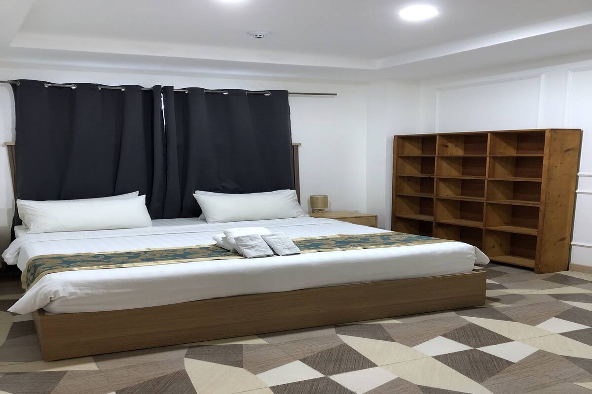 Un dormitorio con cama, un armario de madera y piso estampado.