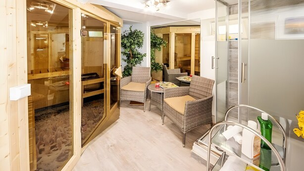 Una habitación con un armario de madera, muebles de mimbre y una puerta de cristal que da a una zona de sauna.