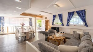 Una sala de estar moderna con sofá, sillas, una mesa de comedor y televisor.