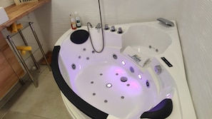 Ein modernes Badezimmer mit einer Badewanne, einer Glasablage für Pflegeprodukte und einem Handtuchhalter.