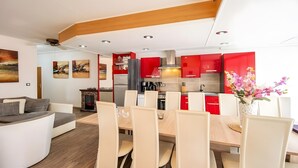 Una cocina moderna con armarios rojos, un comedor con sillas blancas y una chimenea.