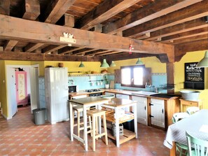 Une cuisine rustique avec des poutres en bois, une cuisinière à gaz, un évier et un tableau noir servant de menu.